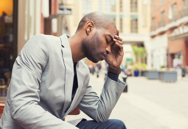 substance induced mood disorder a man sits on a bench on a sidewalk with his head in his hand because of substance induced mood disorder