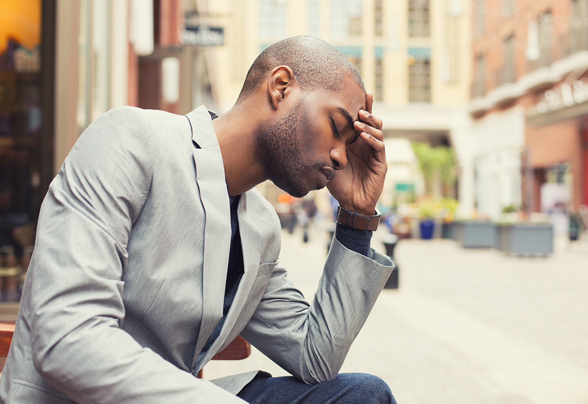 substance induced mood disorder a man sits on a bench on a sidewalk with his head in his hand because of substance induced mood disorder