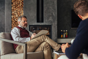 a counselor takes notes in a chair while talking to male patient about buprenorphine treatment