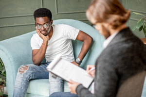 male patient sits on chair and talks to female counselor taking notes in klonopin addiction treatment