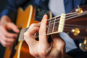 a patient plays the guitar while participating in music therapy