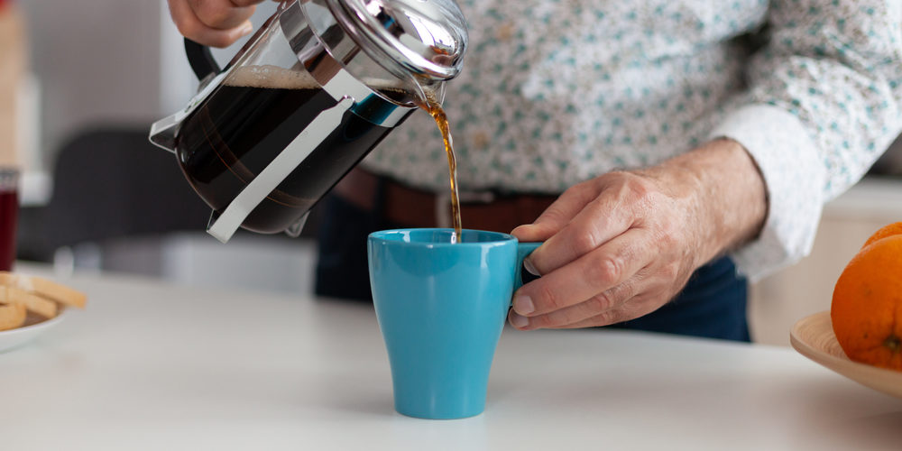 Close,Up,Of,Elderly,Man,Hands,Pouring,Coffee,In,Cup pouring caffeinated drink