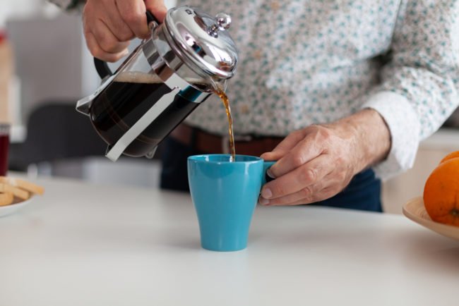 Close,Up,Of,Elderly,Man,Hands,Pouring,Coffee,In,Cup pouring caffeinated drink